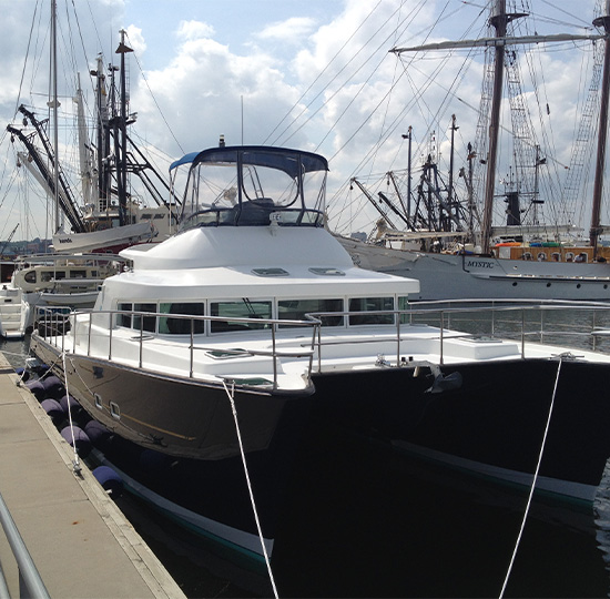Catamaran docked beside historic sailing ships